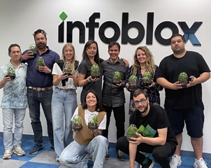Une équipe de neuf employés souriant et tenant des terrariums tout en posant devant un mur avec le logo Infoblox.