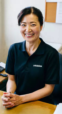デスクで Infoblox のポロシャツを着て笑顔を浮かべている女性。